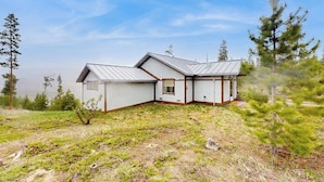 Ett tvåvåningshus med ett sluttande tak, en liten veranda och en inhägnad trädgård.