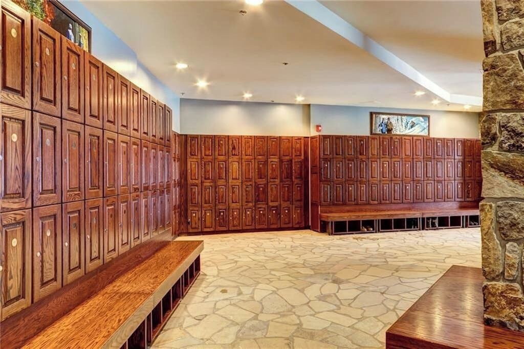 A stone-floored lobby with wooden lockers, benches, and a stone wall.