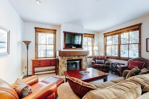 Ein Wohnzimmer mit Kamin, Fernseher und einer Couch.
