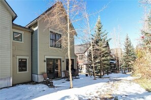 Ein zweistöckiges Haus mit überdachter Terrasse und einem schneebedeckten Garten.