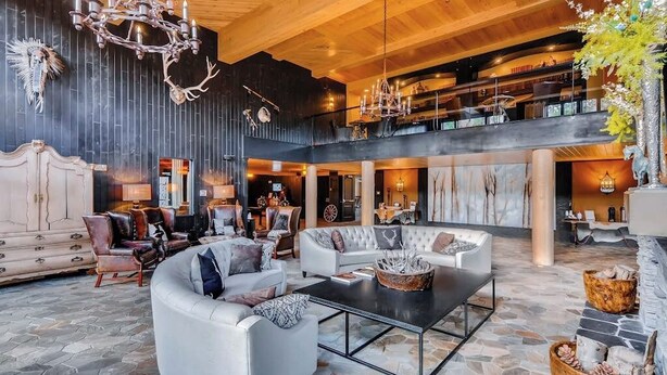 Eine großzügige Lobby mit hoher Decke, einem prunkvollen Kronleuchter und einer Sitzecke mit Ledersofas und einem Couchtisch.