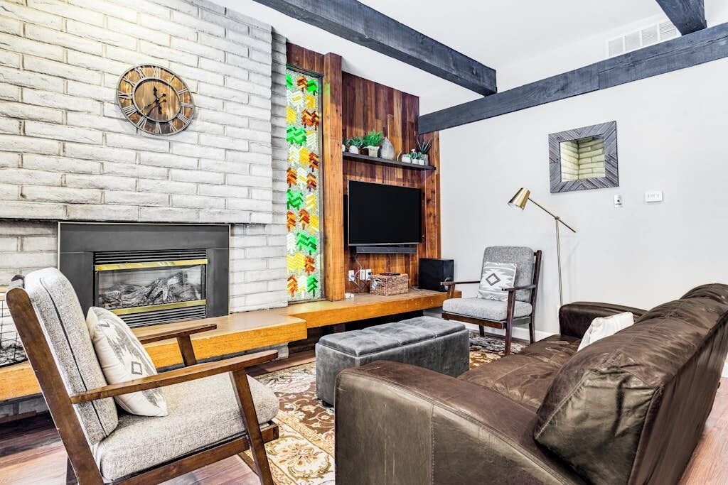 A living room with a fireplace, a clock, a TV, and a sofa.