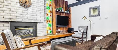 A living room with a fireplace, a clock, a TV, and a sofa.