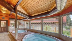 A spa area with two hot tubs, wooden ceiling, and large windows overlooking a building. - Comfy Ski-In Condo w/ Shared Hot Tub & Gas Fireplace - Close to the Mountain (Breckenridge)