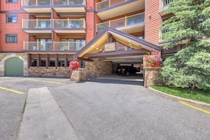 Ein mehrstöckiges Hotel mit überdachter Einfahrt, Steinsäulen und einem Parkplatz.