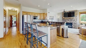 A modern kitchen with wooden cabinets, a central island, a stone fireplace, and recessed lighting. - Stunning house w/ mountain views, free WiFi, outdoor activities (Granby)