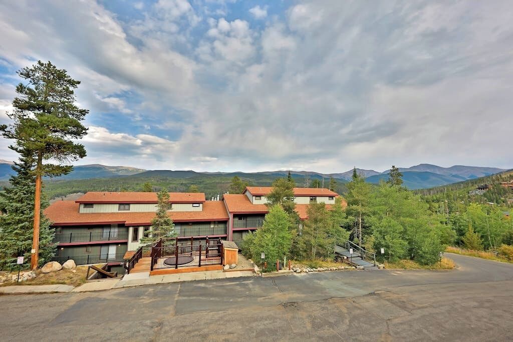 A hotel with multiple buildings, a parking area, and a mountainous backdrop.