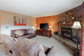 Ein Wohnzimmer mit Kamin aus Stein, einem Fernseher und einem Sofa.