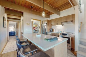 A modern kitchen with a central island, wooden cabinets, and a dining area with bar stools. - Ski In on Crested Butte Mountain, Free Shuttle, Great Views, Renovated (Crested Butte)