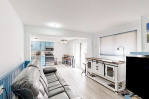 Ein modernes Wohnzimmer mit einer Couch, einem Fernseher und einer Küche im Hintergrund.