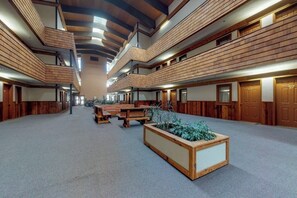 Ein mehrgeschossiges Interieur mit Holzvertäfelung, Bänken und einem zentralen Blumentopf.