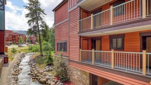 A red building with a balcony, a stone pathway, and a small stream. - Rustic mountain escape with fireplace, W/D, hot tub, & grill - near skiing (Breckenridge)