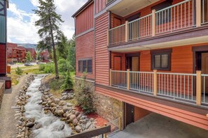 A red building with a balcony, a stone pathway, and a small stream. - Rustic mountain escape with fireplace, W/D, hot tub, & grill - near skiing (Breckenridge)