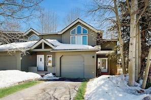 A residential house with a garage, a covered porch, and a snow-covered driveway. - Renovated condo with deck, mountain view, fireplace & gorgeous kitchen (Crested Butte)