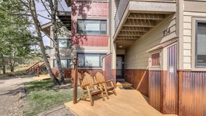 Ein mehrstöckiges Gebäude mit einer Holzterrasse und Sitzgelegenheiten im Freien.