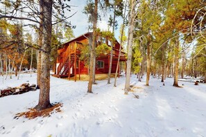 Eine Hütte, umgeben von Bäumen in einer verschneiten Landschaft.