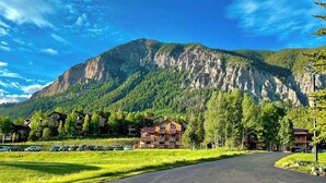 A mountain resort with a paved road, buildings with balconies, and a parking area.