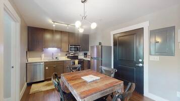 A modern kitchen with dark wood cabinets, stainless steel appliances, and a dining table with chairs.