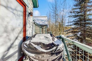 A covered grill outside a building with a metal railing and snow-covered trees in the background. - Main Street condo with mountain view, fireplace, pool & hot tubs - walk to lifts (Breckenridge)