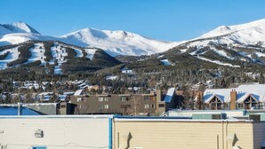 A mountainous landscape with snow-covered peaks and a residential area with buildings and a ski slope. - Main Street condo with mountain view, fireplace, pool & hot tubs - walk to lifts (Breckenridge)