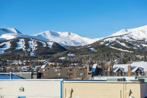 A mountainous landscape with snow-covered peaks and a residential area with buildings and a ski slope. - Main Street condo with mountain view, fireplace, pool & hot tubs - walk to lifts (Breckenridge)