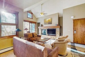 A living room with a fireplace, a sofa, a coffee table, and a television. - Main Street condo with mountain view, fireplace, pool & hot tubs - walk to lifts (Breckenridge)