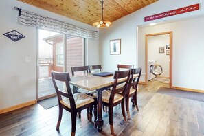 A dining area with a wooden table and chairs, a ceiling fan, and a view of the outside.