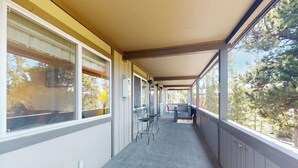 Un pasillo cubierto con ventanas, sillas y una mesa.