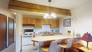 Una cocina con armarios de madera, una estufa blanca, un microondas y una isla de madera con taburetes de bar.