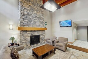 A living room with a stone fireplace, a flat-screen TV, and a sofa.