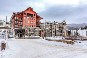 A multi-story hotel with a stone facade, a red upper level, and a snow-covered landscape.
