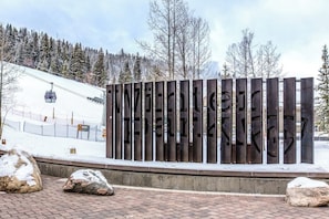A wooden sign with the text 'TENNISBERG' in a mountainous area with a ski lift in the background.