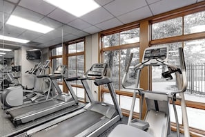 Ein Fitnessstudio mit Laufbändern, Crosstrainern und einem Ergometer.