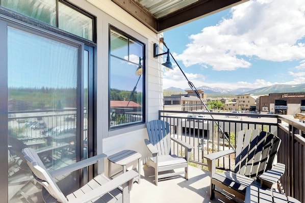Ein Balkon mit Bergblick, ein Stuhl, ein Tisch und eine Lampe.