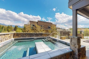 Ein Pool mit Steinwänden, einer Steinterrasse und Blick auf Berge.