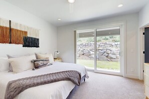 Ein Schlafzimmer mit einem großen Bett, einer Steinsäule im Außenbereich und einer Schiebeglasdoor.
