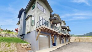 Un edificio residencial de varios pisos con garaje, balcón y entrada para vehículos.