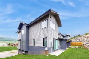 Ein modernes, zweistöckiges Haus mit geneigtem Dach, großen Fenstern und einer Steinmauer.