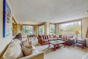 Ein Wohnzimmer mit einer Eckcouch, einem Couchtisch und einem Essbereich mit Tisch und Stühlen.