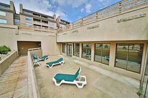Eine Dachterrasse mit Liegestühlen, einem Pool und einem Gebäude mit großen Fenstern.