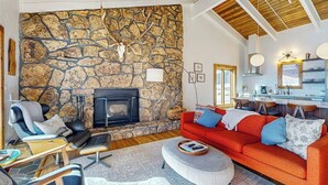 Ein Wohnzimmer mit Steinwand, Kamin, einem roten Sofa und einem modernen Sessel.