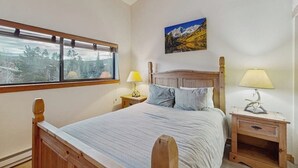 A bedroom with a bed, two bedside tables, a window with a view, and a painting on the wall. - Cozy condo with easy ski access, W/D, fully stocked kitchen & great location (Breckenridge)