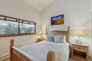 A bedroom with a bed, two bedside tables, a window with a view, and a painting on the wall. - Cozy condo with easy ski access, W/D, fully stocked kitchen & great location (Breckenridge)