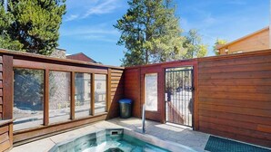 A wooden deck with a hot tub, large windows, and a metal gate. - Cozy condo with easy ski access, W/D, fully stocked kitchen & great location (Breckenridge)