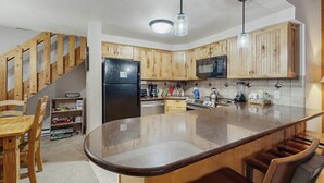A kitchen with wooden cabinets, a central island, a refrigerator, and a microwave. - Cozy condo with easy ski access, W/D, fully stocked kitchen & great location (Breckenridge)