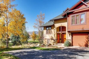 Ein zweistöckiges Haus mit Garage, einer Veranda und einer Auffahrt.