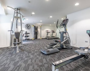 Ein Fitnessstudio mit Laufbändern, Crosstrainern und Gewichten.