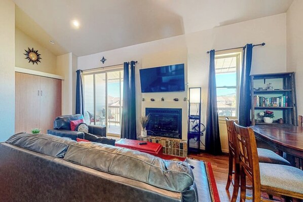 A living room with a sofa, a TV, a bookshelf, and a dining area.