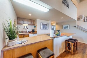 A kitchen with wooden cabinets, a countertop, and a bar area with stools.