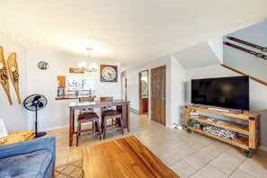 A living room with a TV, wooden furniture, a dining area, and a staircase. - Two-story, dog-friendly townhouse with a washer/dryer & a full kitchen (Pagosa Springs)